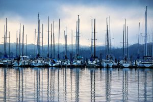Apartments in Farragut Sailboats moored at a marina during dusk with calm water reflecting masts under a cloudy sky, captured by Jack Kevin Keller.