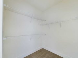 Apartments in Farragut An empty white-walled closet with four wire shelves installed on the walls and a beige carpeted floor, perfect for organizing your essentials in rental properties.