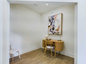 Apartments in Farragut Small, minimalist room featuring a wooden desk with a chair, abstract artwork on the wall, and neutral-colored decor. The floor is light wood, and the walls are painted white.