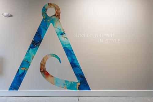 Apartments in for rent Farragut TN Wall art featuring a large stylized letter 'A' with ocean-themed colors and the words Anchor yourself in style on a light-colored background. Anchor 934 Apartments in Biddle Farms Town Center