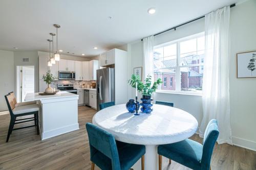 Apartments in for rent Farragut TN Bright kitchen and dining area with a round table, blue chairs, and modern appliances. Large window allows natural light. Anchor 934 Apartments in Biddle Farms Town Center