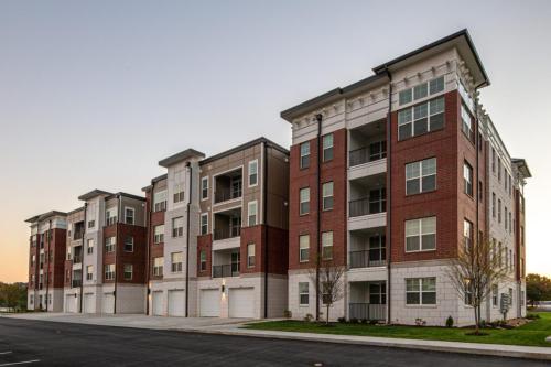 Apartments in for rent Farragut TN A row of modern four-story apartment buildings with balconies and garages, set against a clear sky. Anchor 934 Apartments in Biddle Farms Town Center