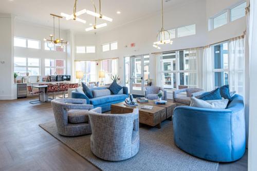 Apartments in for rent Farragut TN A modern living room with blue and gray seating, a wooden coffee table, large windows, and contemporary chandeliers. Anchor 934 Apartments in Biddle Farms Town Center