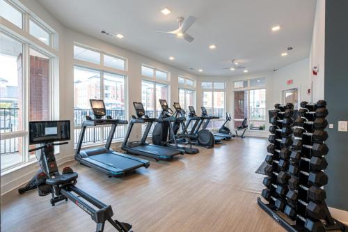 Apartments in for rent Farragut TN A gym room with treadmills, rowing machines, and a rack of dumbbells. Large windows provide natural light. Anchor 934 Apartments in Biddle Farms Town Center