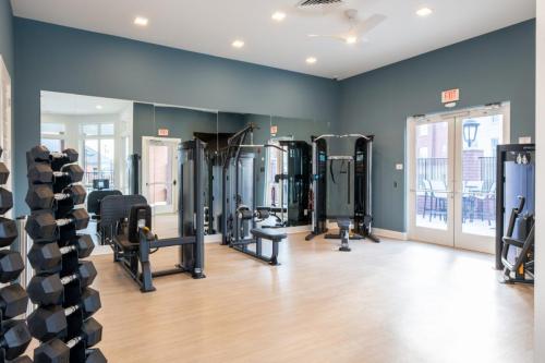 Apartments in for rent Farragut TN A modern gym with weight machines, free weights, and mirrored walls. Natural light enters through glass doors. Anchor 934 Apartments in Biddle Farms Town Center