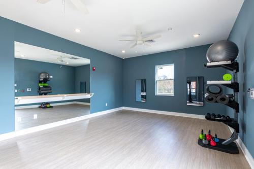 Apartments in for rent Farragut TN A fitness room with mirrored walls, exercise balls, and various weights on a rack. The room has wooden flooring and blue walls. Anchor 934 Apartments in Biddle Farms Town Center