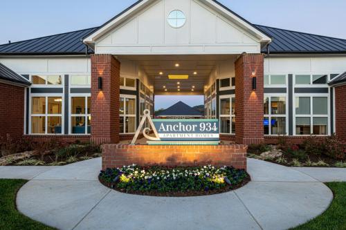 Apartments in for rent Farragut TN Front view of the Anchor 934 Apartment Homes entrance with a brick facade and landscaping, featuring a sign displaying the name. Anchor 934 Apartments in Biddle Farms Town Center