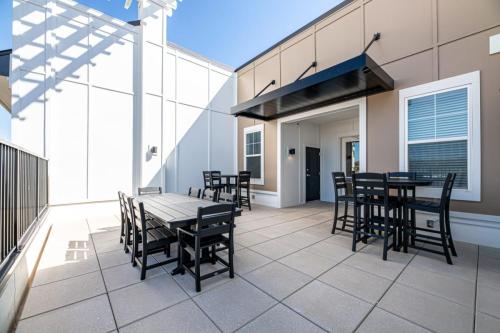 Apartments in for rent Farragut TN Outdoor patio with black tables and chairs on beige tiled flooring, adjacent to a building wall with large windows and a black awning. Anchor 934 Apartments in Biddle Farms Town Center