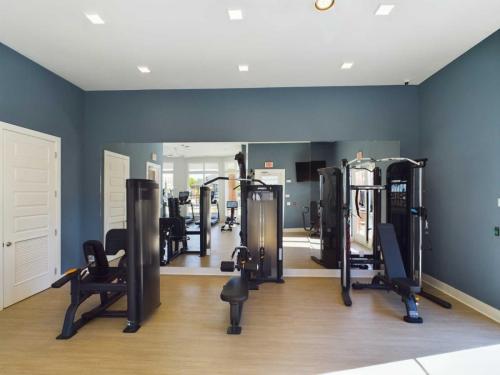 Apartments in for rent Farragut TN A gym room with exercise machines, including a seated cable row and a multi-functional trainer, against blue walls and a large mirror. Anchor 934 Apartments in Biddle Farms Town Center