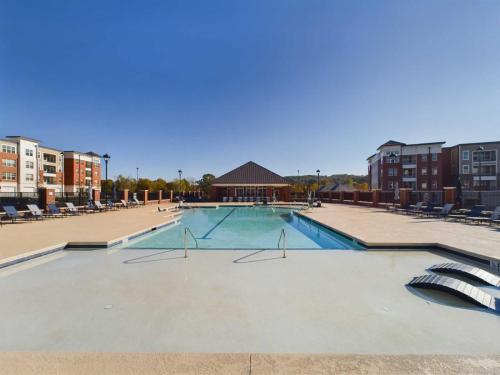 Apartments in for rent Farragut TN Outdoor apartment complex pool with clear water, surrounded by lounge chairs and buildings under a clear blue sky. Anchor 934 Apartments in Biddle Farms Town Center