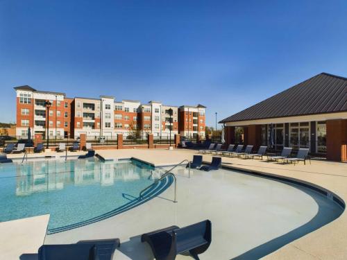 Apartments in for rent Farragut TN Outdoor swimming pool area with lounge chairs and a nearby building under a clear blue sky. Anchor 934 Apartments in Biddle Farms Town Center