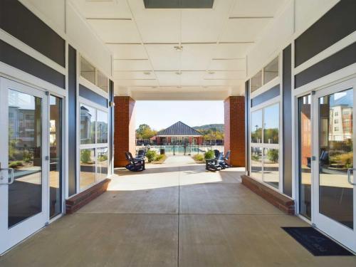 Apartments in for rent Farragut TN Covered walkway with glass doors on sides leading to an outdoor area with chairs and a distant building. Anchor 934 Apartments in Biddle Farms Town Center