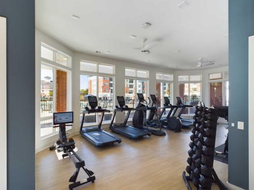 Apartments in for rent Farragut TN A modern gym with several treadmills, an elliptical, a stationary bike, and a rack of dumbbells. Large windows provide natural light. Anchor 934 Apartments in Biddle Farms Town Center