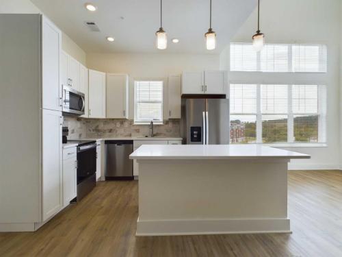 Apartments in for rent Farragut TN Modern kitchen with white cabinets, stainless steel appliances, and an island with pendant lighting. Large windows allow natural light, and hardwood floors complete the space. Anchor 934 Apartments in Biddle Farms Town Center