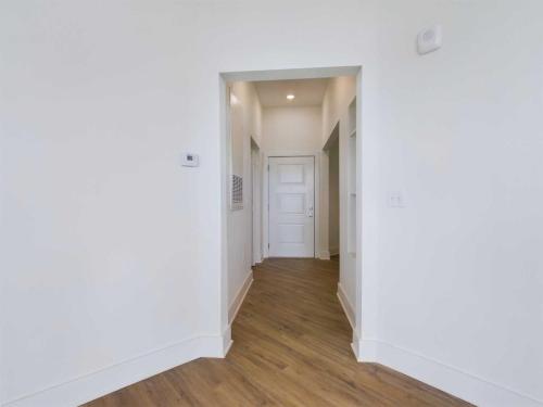 Apartments in for rent Farragut TN A hallway with light-colored walls and hardwood flooring, leading to a closed white door. Anchor 934 Apartments in Biddle Farms Town Center