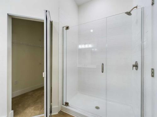 Apartments in for rent Farragut TN A clean, empty shower area with glass doors and white tiles next to an open closet with shelves. Anchor 934 Apartments in Biddle Farms Town Center