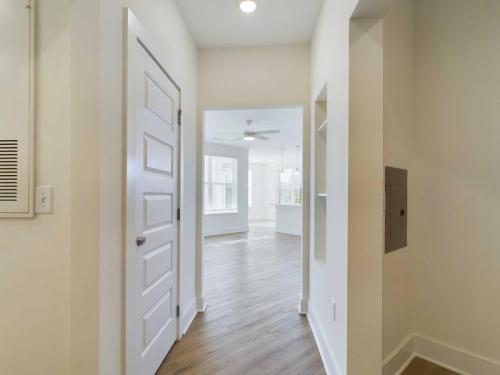 Apartments in for rent Farragut TN A bright hallway with wooden flooring leads to an open living space with large windows, white walls, and a ceiling fan. Anchor 934 Apartments in Biddle Farms Town Center