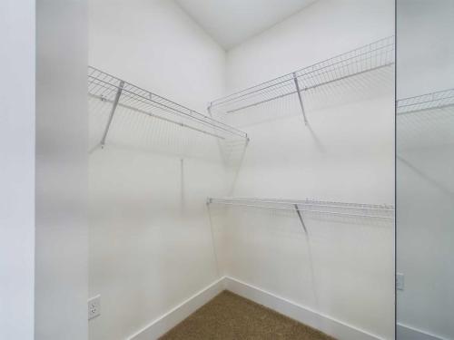 Apartments in for rent Farragut TN Empty walk-in closet with white walls, carpeted floor, and metal wire shelving on three sides. Anchor 934 Apartments in Biddle Farms Town Center