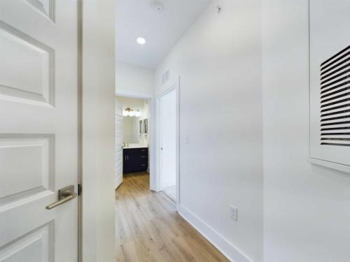 Three Bedroom Apartment Sailor Apt. 1-201 Apartments in for rent Farragut TN View of a bright hallway with white walls and a wooden floor, leading to a bathroom with a mirror and a sink. The door on the left is partially open. Anchor 934 Apartments in Biddle Farms Town Center