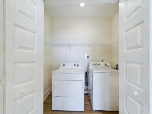 Apartments in for rent Farragut TN A laundry room with a white washing machine and dryer side by side, under a wire shelf, enclosed in a space with open double doors. Anchor 934 Apartments in Biddle Farms Town Center