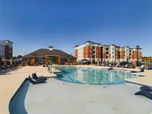 Apartments in for rent Farragut TN Swimming pool area surrounded by lounge chairs and modern apartment buildings under a clear blue sky. Anchor 934 Apartments in Biddle Farms Town Center