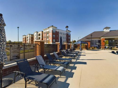 Apartments in for rent Farragut TN Poolside area with sun loungers and umbrellas on a sunny day. Brick buildings with multiple floors are visible in the background. Anchor 934 Apartments in Biddle Farms Town Center