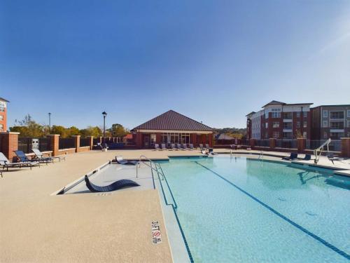 Apartments in for rent Farragut TN Outdoor swimming pool with deck chairs around it, adjacent to a red-brick building under a clear blue sky. Anchor 934 Apartments in Biddle Farms Town Center