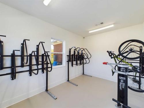 Apartments in for rent Farragut TN Bike storage room with wall-mounted racks and one bicycle on a repair stand. White walls and ceiling with overhead lights. Anchor 934 Apartments in Biddle Farms Town Center