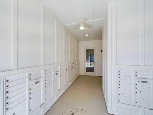 Apartments in for rent Farragut TN A narrow hallway with rows of white mailboxes on each side leading to a closed glass door. Anchor 934 Apartments in Biddle Farms Town Center