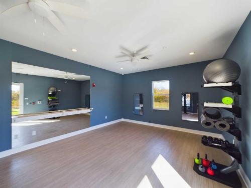 Apartments in for rent Farragut TN A gym room with blue walls, a large mirror, and exercise equipment, including kettlebells, mats, and stability balls, is neatly organized on shelves. Anchor 934 Apartments in Biddle Farms Town Center