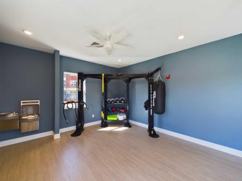 Apartments in for rent Farragut TN A room with blue walls features exercise equipment, including a punching bag, kettlebells, ropes, and a multifunctional gym station. A water fountain is in the corner. Anchor 934 Apartments in Biddle Farms Town Center