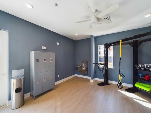 Apartments in for rent Farragut TN A gym room with lockers, a trash can, a water fountain, and exercise equipment, including resistance bands and weights, against blue walls and wood flooring. Anchor 934 Apartments in Biddle Farms Town Center