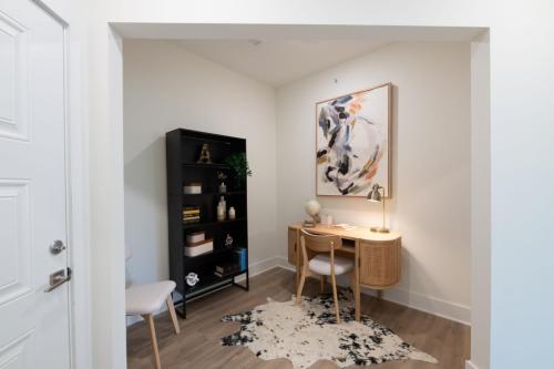 Apartments in for rent Farragut TN Small home office with a wooden desk, chair, and lamp. Abstract art on the wall, books and decor on a black shelf, and a cowhide rug on the floor. Anchor 934 Apartments in Biddle Farms Town Center