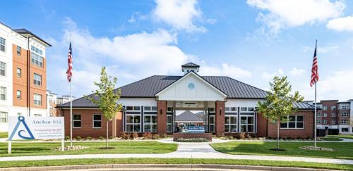 Apartments in for rent Farragut TN Exterior of a brick building with a sign reading Anchor 934 Apartments, surrounded by grass, trees, and two American flags. Anchor 934 Apartments in Biddle Farms Town Center