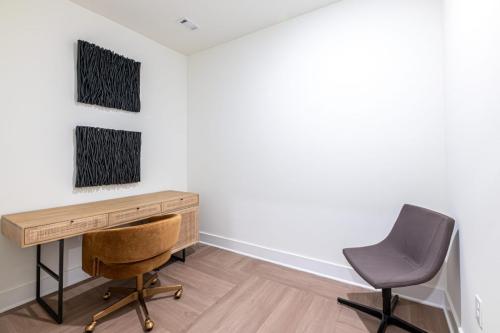 Apartments in for rent Farragut TN Minimalist room with two modern chairs, a wooden desk, and dark wall art. The floor is light wood, and the walls are white. Anchor 934 Apartments in Biddle Farms Town Center